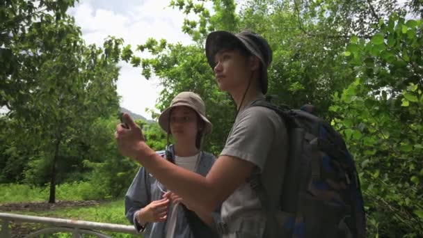 两名亚洲青少年背包客在热带森林公园徒步旅行时 用手机定位应用程序寻找方向 夏季户外活动 移动技术和信号波搜索 Uhd — 图库视频影像