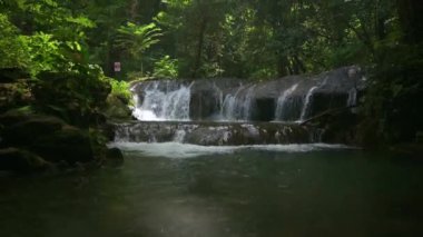 Yağmur ormanlarındaki yemyeşil bitkilerle çevrili kayaların üzerinden akan suyla dolu Idyllic şelale sahnesi. Atışı kaldırıyorum. Sa Nang Manora Şelalesi. Phang Nga Eyaleti. Tayland.