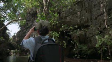 Sırt çantalı Asyalı kadın yürüyüşçü yaz aylarında Rocky Mountain Ormanı 'nda fotoğraf ve video çekerken cep telefonunu tarıyor. Açık hava takibi. Boş zaman aktivitesi. Tek başına seyahat yaşam tarzı.