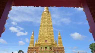 Kapıdan içeri girip, bulutlu mavi gökyüzü ile Budist tapınağındaki muhteşem altın pagoda 'ya hayran kaldım. Wat Mahathat Wachiramongkhon ya da Wat Bang Thong, Krabi Eyaleti, Tayland.