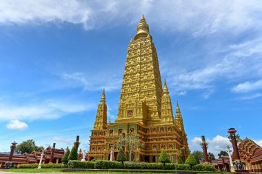 Muhteşem altın pagoda, tapınağında bulutlu mavi gökyüzü olan güzel yeşil bahçeyle çevrili. Wat Mahathat Wachiramongkhon ya da Wat Bang Thong, Krabi Eyaleti, Tayland.