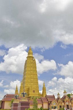 Bulutlu mavi gökyüzünün altındaki Budist manastırındaki büyük altın pagoda 'nın dikey çarpıcı fotoğrafı. Wat Mahathat Wachiramongkhon ya da Wat Bang Thong, Krabi Eyaleti, Tayland.