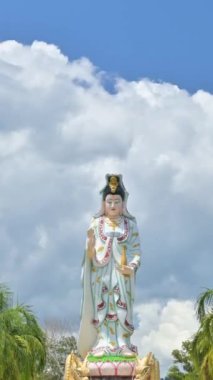 Büyük Guanyin 'in (Merhamet Tanrıçası) muhteşem manzarası. Hızlı hareket eden zaman dilimi ile heykel bulutlu mavi gökyüzünden uzaklaşır. Wat Bang Riang (Wat Rat Upatam) Tayland 'ın Phang Nga eyaletinde güzel bir tepe tapınağıdır..