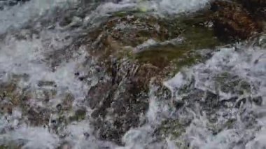 Şelale mesafesinden güneş ışığı altındaki kayalıklara akan hızlı ve taze su. Su sıçrıyor.. 