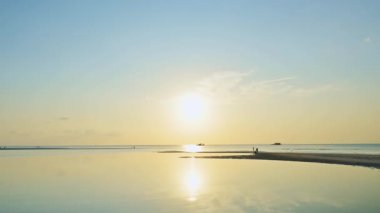 Gün batımında Koh Samui 'de güzel bir kıyı manzarası. Dalgalar çekildiğinde sahilde yürüyen birçok insanın dramatik bir şekilde su yüzeyine yansıyan görüntüsü..