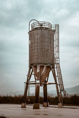 Rustic Wooden Water Tower Under Dramatic Cloudy Sky clipart