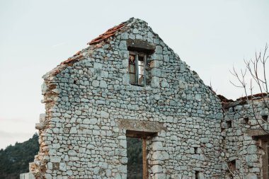 Hırvatistan 'ın Dalmaçya kentinde engebeli bir dağ manzarasının ortasındaki Taş Ev kalıntıları