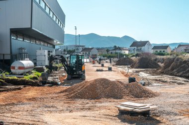 METKOVIC, CROATIA - December 7, 2024: Construction of a new road with workers, excavators, and gravel piles under a clear sky clipart