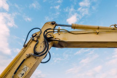 İnşaat alanında Pistons ve Hortumlarla Açık Mavi Gökyüzüne Karşı Hidrolik Kazıcı Kolu