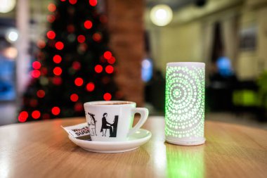 Cozy Coffee Moments with Festive Christmas Lights and Artistic Ceramic Cup. Warm Holiday Vibes in a Modern Caf Setting clipart