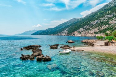 Hırvatistan 'daki Peljesac Yarımadası' nın Sahra Sahili 'nde Adriyatik Denizi ve Dingac Bölgesi' ndeki Rocky Shoreline yer alıyor. Kristal berrak deniz, gökyüzü ve sahil.