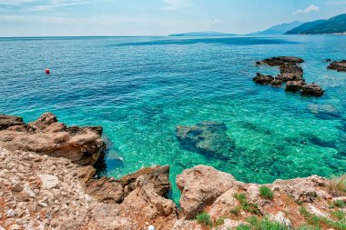 Hırvatistan 'daki Peljesac Yarımadası' nın Sahra Sahili 'nde Adriyatik Denizi ve Dingac Bölgesi' ndeki Rocky Shoreline yer alıyor. Kristal berrak deniz, gökyüzü ve sahil.