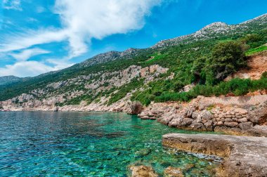 Hırvatistan 'daki Peljesac Yarımadası' nın Sahra Sahili 'nde Adriyatik Denizi ve Dingac Bölgesi' ndeki Rocky Shoreline yer alıyor. Kristal berrak deniz, gökyüzü ve sahil.