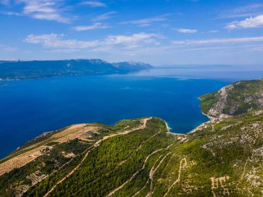 Güney Hırvatistan üzüm bağları ve Kremena ve Komarna yakınlarındaki Adriyatik kıyı şeridi, manzaralı yuvarlanan tepeler, yemyeşil üzüm bağları ve uzakta adaları olan açık mavi deniz