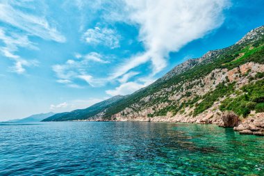 Hırvatistan 'daki Peljesac Yarımadası' nın Sahra Sahili 'nde Adriyatik Denizi ve Dingac Bölgesi' ndeki Rocky Shoreline yer alıyor. Kristal berrak deniz, gökyüzü ve sahil.