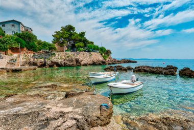 Hırvatistan 'daki Peljesac Yarımadası' nın Sahra Sahili 'nde Adriyatik Denizi ve Dingac Bölgesi' ndeki Rocky Shoreline yer alıyor. Kristal berrak deniz, gökyüzü ve sahil.