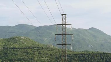 Yüksek voltajlı güç iletim kulesi birden fazla yalıtkan ve elektrik kabloları ile sisli bir dağ manzarası boyunca uzanıyor. Çoklu çekim.