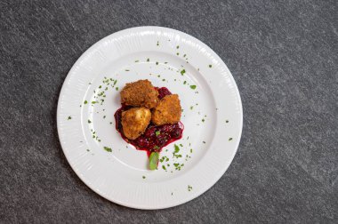 Beyaz tabakta tatlı kızılcık soslu kızarmış Camembert peyniri. Gurme Aperatif Yemekler ve Tatil Menüleri İçin Mükemmel