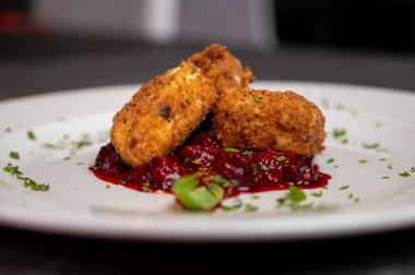 Beyaz tabakta tatlı kızılcık soslu kızarmış Camembert peyniri. Gurme Aperatif Yemekler ve Tatil Menüleri İçin Mükemmel