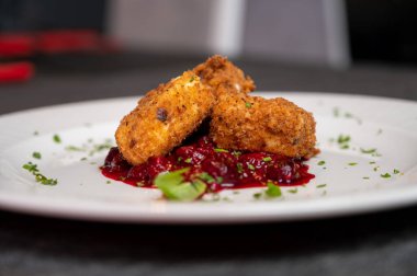 Beyaz tabakta tatlı kızılcık soslu kızarmış Camembert peyniri. Gurme Aperatif Yemekler ve Tatil Menüleri İçin Mükemmel