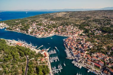 Hırvatistan 'ın Brac adasındaki Milna kasabası ve marinasının havadan görünüşü, yelkenliler, eski taş evler ve yaz ışığında Akdeniz manzarası