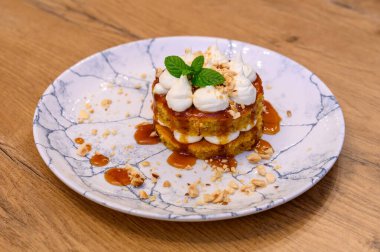 Karamel, fındık, sünger keki ve mermer bir tabakta krema ile gurme tatlı, iyi yemek restoranında kırsal ahşap bir masada servis edilir..