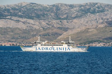 Ayrıl, Hırvatistan. 16 Temmuz 2019: Jadrolinija feribotu Marjan, arka planda Dalmaçya kıyı şeridi ve Mosor dağlarıyla Adriyatik Denizi 'ne yelken açıyor