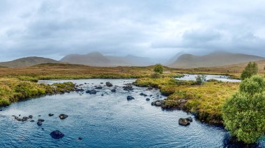 Glencoe, İskoçya 'da fırtınalı, gri gökyüzü olan muhteşem bir dağ manzarası.