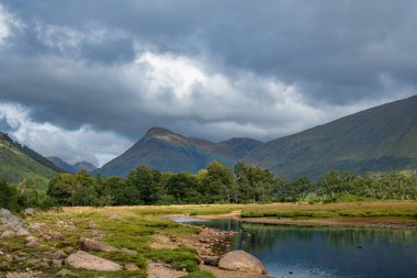 Gölün suları çevredeki dağları yansıtıyor. Uzaklarda Ben Cruachan 'ın karla kaplı zirvesi, İskoçya, Argyll ve Bute.