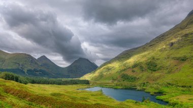 Gölün suları çevredeki dağları yansıtıyor. Uzaklarda Ben Cruachan 'ın karla kaplı zirvesi, İskoçya, Argyll ve Bute.