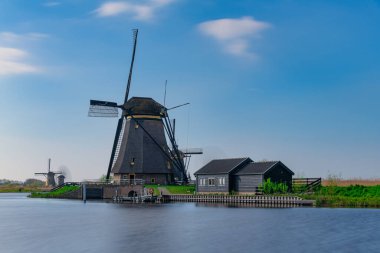 Hollanda 'nın dramatik akşam ışığında bir kanal boyunca rüzgar değirmeni