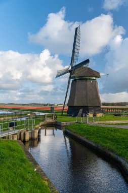 Hollanda 'nın dramatik akşam ışığında bir kanal boyunca rüzgar değirmeni