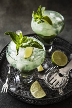 Nane aromalı bir bardak içecek, arka planda soğuk yaz içeceği.