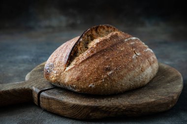 Tahta üzerinde çıtır çıtır ve yumuşak kabuklu leziz hava ekmeği, sığ alan derinliği olan seçici bir odak noktası.