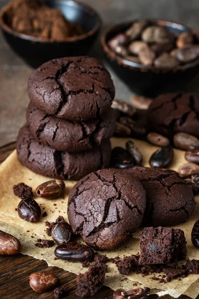 Delicious   chocolate  cookies  and   cocoa beans on wooden table, selective focus