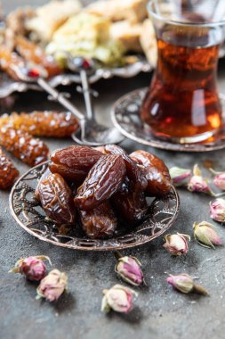 Geleneksel bardaklarda Türk çayı ve ahşap arka planda hurma meyveleri
