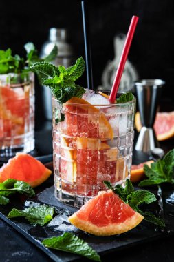 Esmer arka planda greyfurt kokteyli ve bar aksesuarlı bardaklar. Atmosferik yemek fotoğrafı, seçici odak