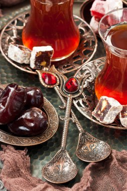 Geleneksel tarzda servis edilen bir fincan Türk çayı ve koyu arkaplanda Türk lezzeti.