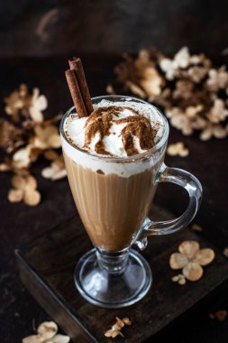 Koyu ahşap arka planda cam bardakta balkabağı baharatlı latte ile kompozisyon