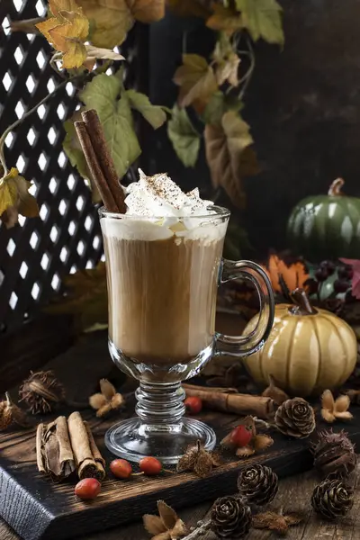 Sonbahar kompozisyonu, sonbahar yaprakları, balkabağı aromalı latte, ahşap masa. Mevsimlik rahatlama ve düşüş konsepti