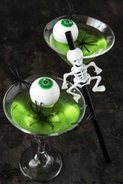 Cadılar Bayramı yeşil kokteyli. İçki konsepti, karanlık arka planda iskelet tatil süslemeli bardaklar.