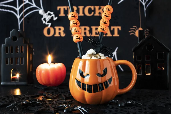 Halloween decoration and horror concept -  mug with hot drink, spiders and cobweb over dark background