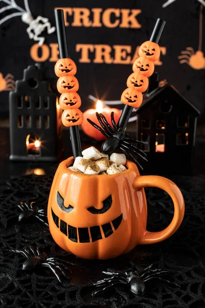 Halloween decoration and horror concept -  mug with hot drink, spiders and cobweb over dark background