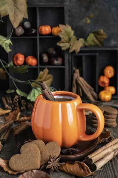 Mug  of autumn pumpkin latte with whipped cream and spices. Coffee with pumpkin and cinnamon on wooden  background