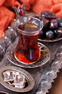 Cam bardakta çay ve ahşap zeminde bakır tepside Türk Lokumu