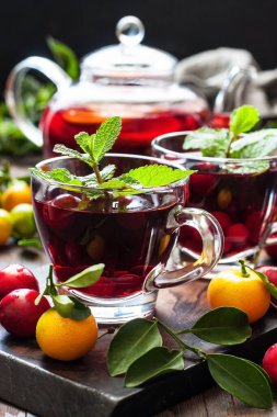 Cam fincanlarda çilek çayı ve koyu ahşap masada çaydanlık, sığ alan derinliğinde seçici bir odak.