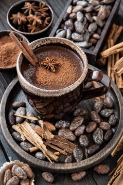 Tarçın çubuklu sıcak çikolata, ahşap arka planda anason ve kakao tozu.