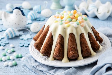 Lezzetli paskalya pastası, seramik tavuk ve ahşap masa üzerinde dekoratif yumurtalar.