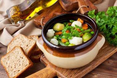 Rustik ahşap arka plan üzerinde havuç, karnabahar, maydanoz, bezelye ve yeşil fasulye ile Sebze çorbası 