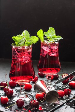 Kiraz suyu, buz küplü kokteyl, nane yaprağı ve olgun tatlı kirazlar.